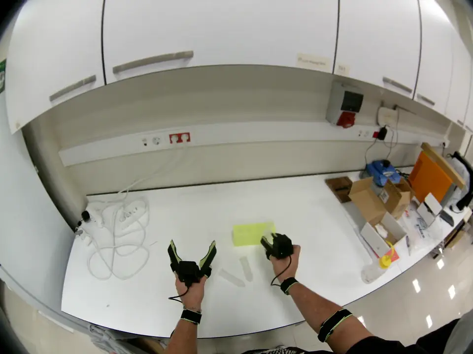 Head-camera view of a white lab bench with both grippers handling tubes next to a rack